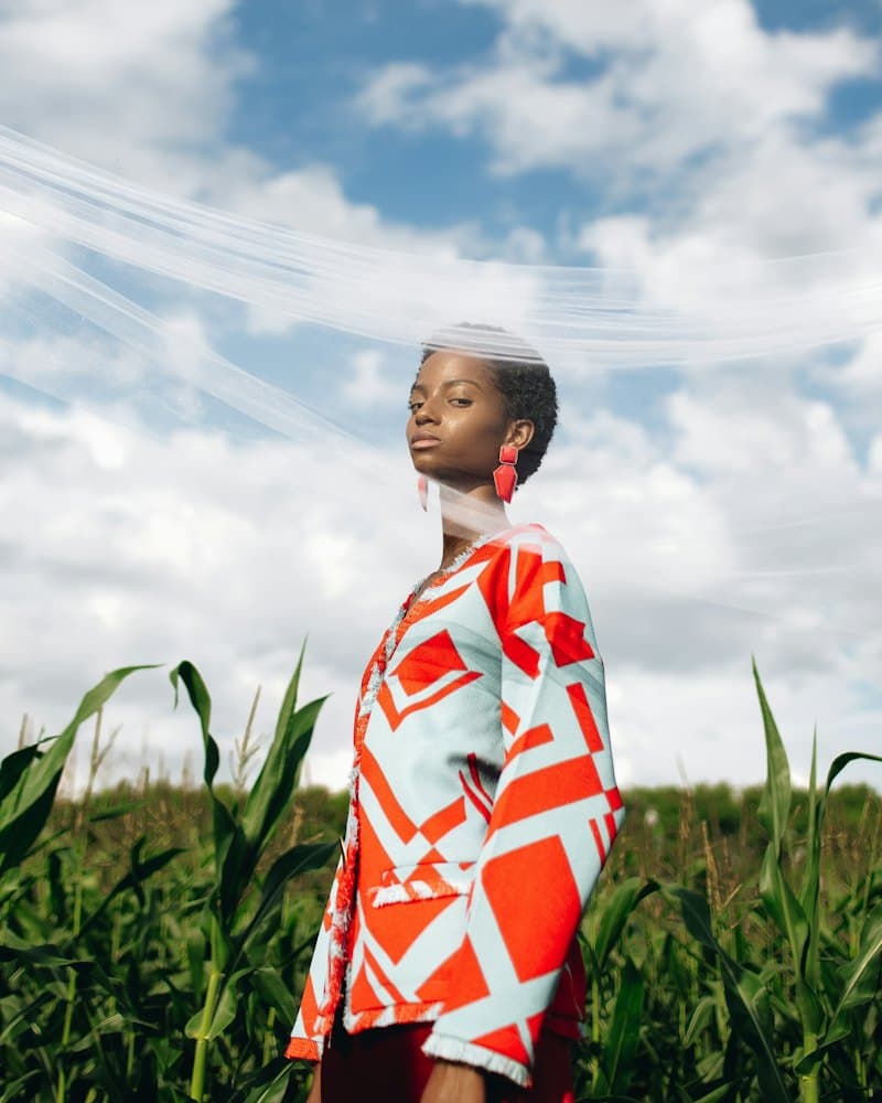 Model in a red and white graphic jacket standing in a cornfield