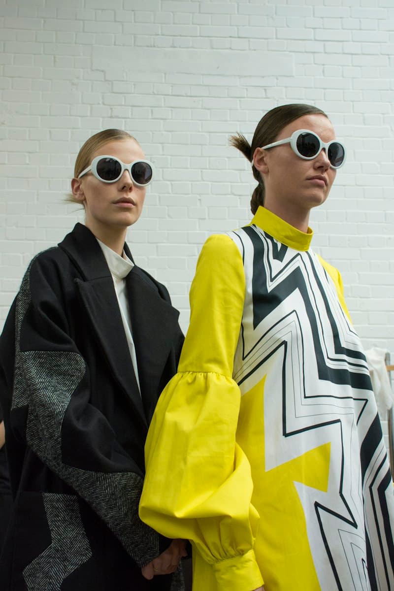 Two models in white sunglasses, one in a yellow graphic dress