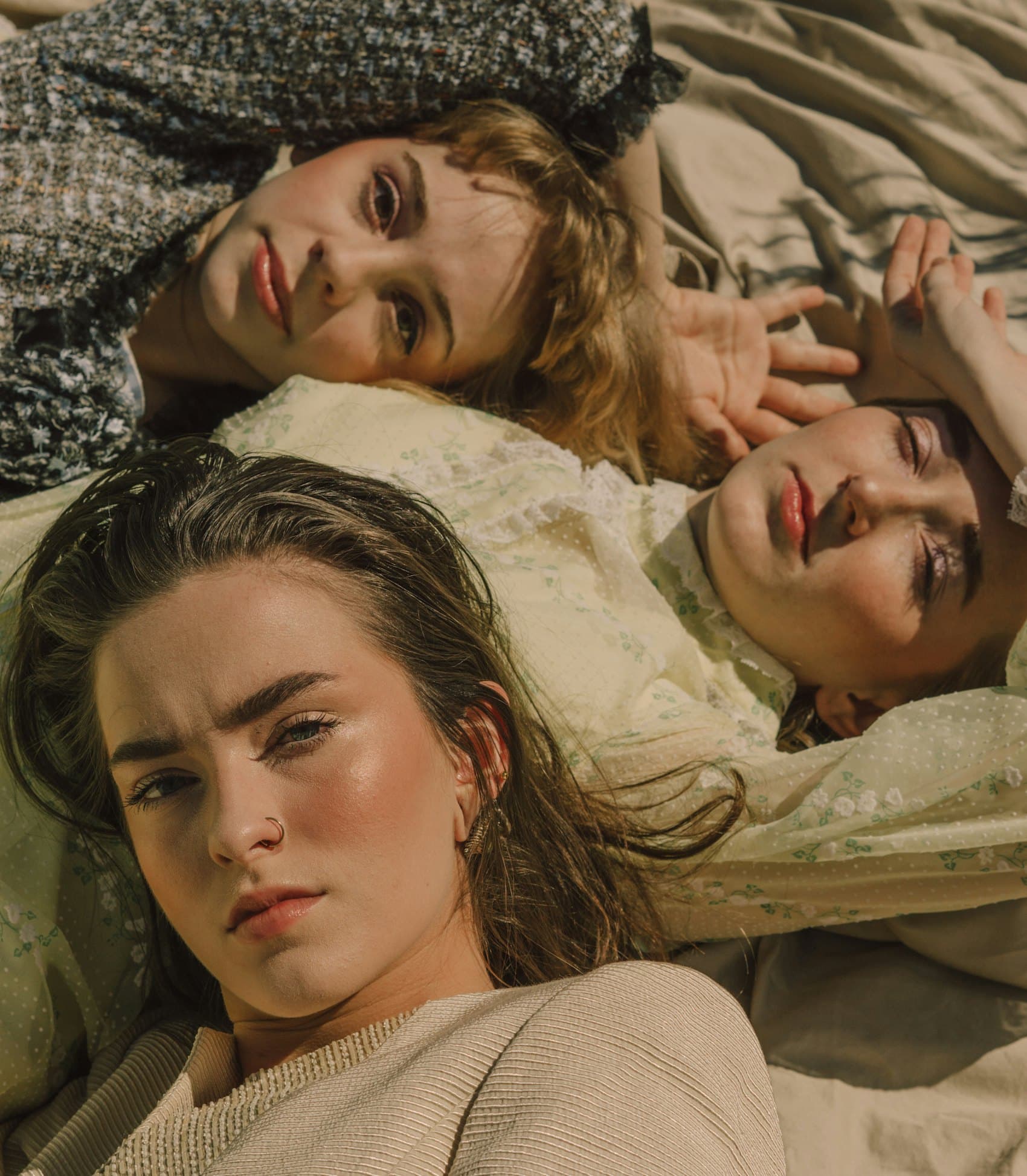 Three models lying together on crumpled linen