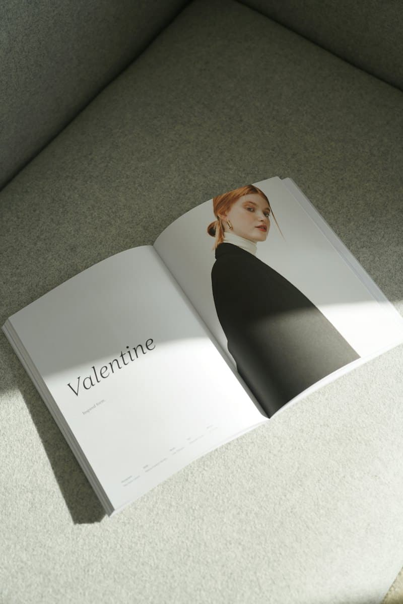 An open fashion magazine resting on a grey sofa