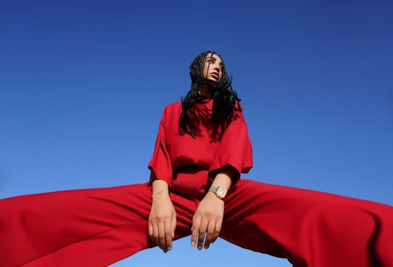 Model in an oversized red set against a clear blue sky